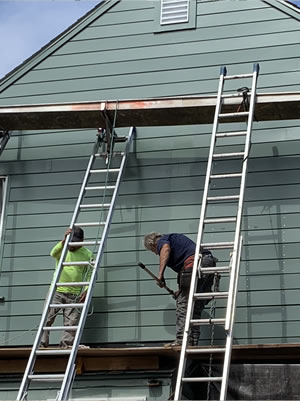 Roofing crew working from ladders on a home exterior